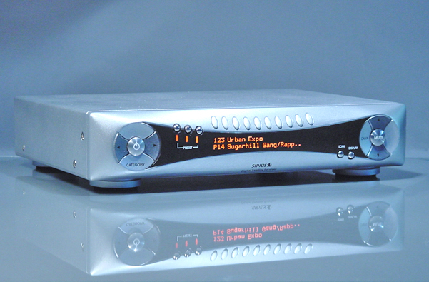 Angled view of a silver-finish digital receiver with large tactile buttons and a segmented LED display.