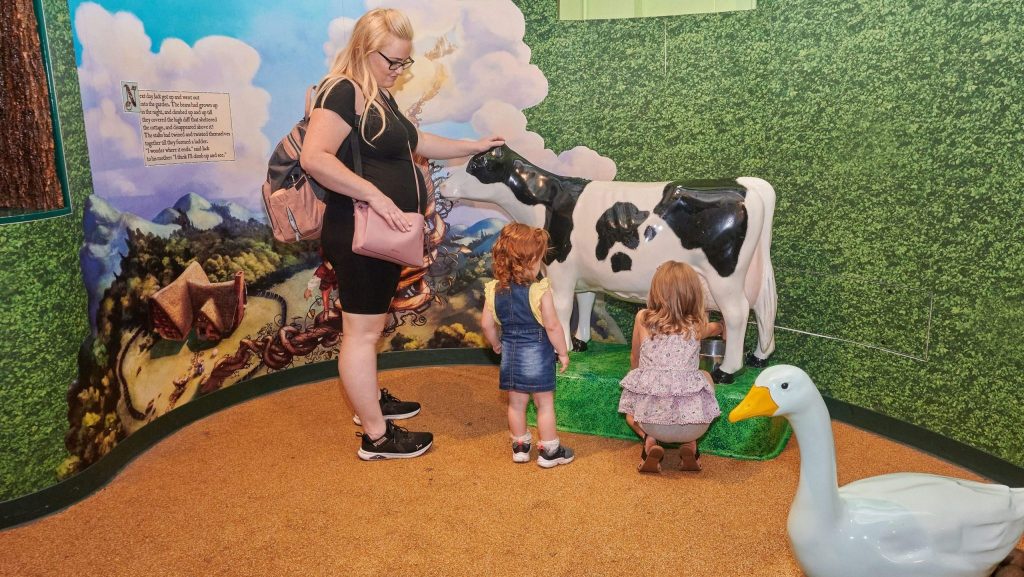 Post-installation photograph of mother and children with life-sized cow and mural backdrop — a visual remnant of the exhibit’s legacy