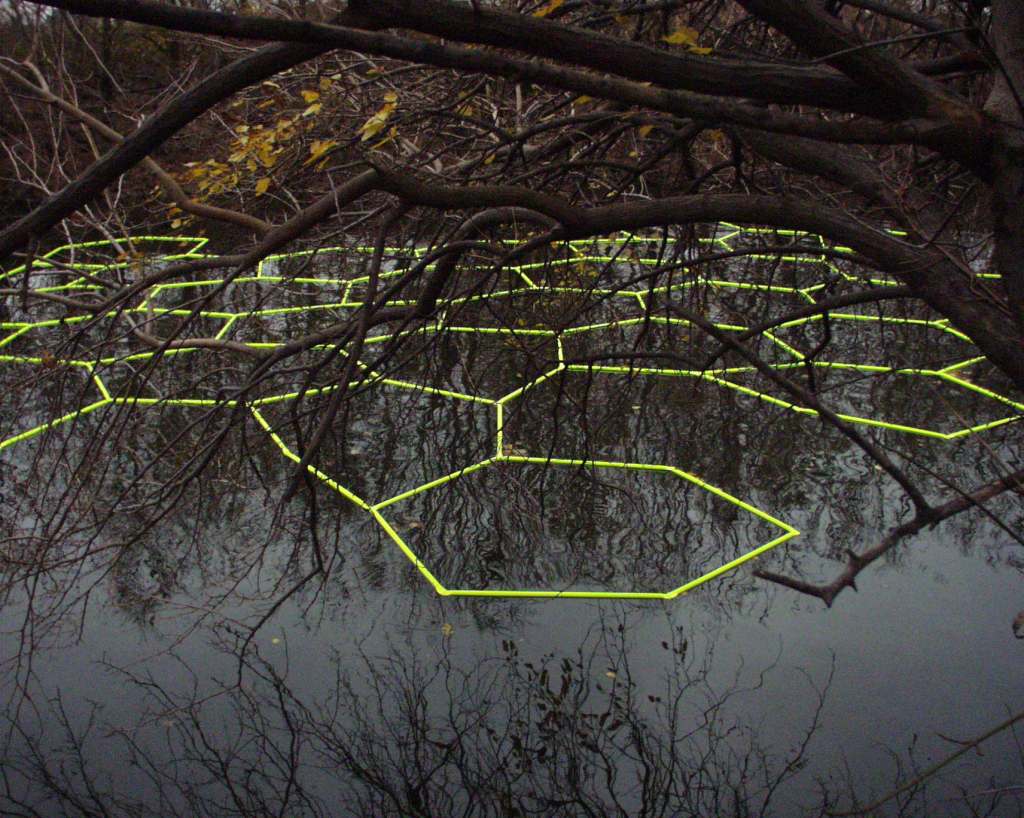 "Close-up of interlocked hexagon surfaces shifting with tide—kinetic interaction with flow."