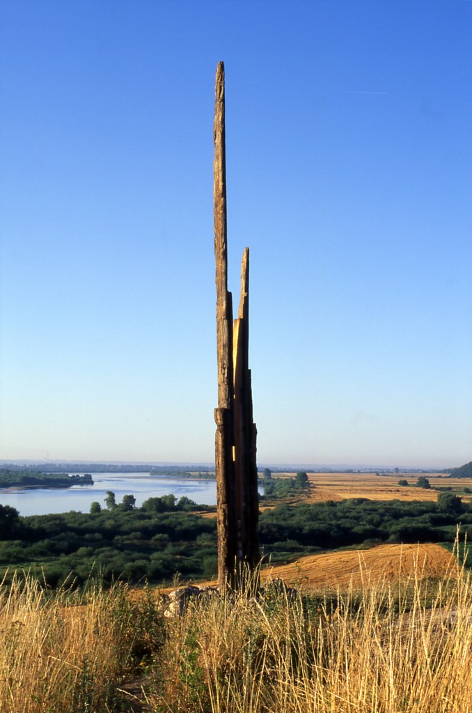 "Wind-whipped layered timber structures on elevated plateau—vibrational dialogue with landscape."