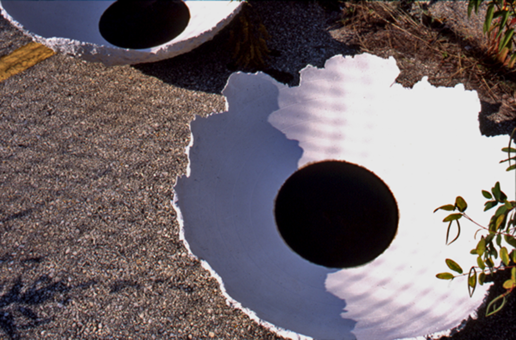 "Oil-filled hydrocal basins arranged outdoors—symbol of environmental residue and cultural erosion."