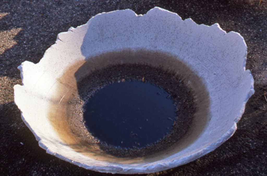 Close-up of Blowback's textured hydrocal basin with rippled interior containing dark oil pool in Edward Dormer's Philadelphia art installation